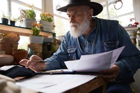 Aged male florist making financial reports in own shop