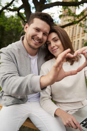 Happy couple making heart symbol with hands on the streetの写真素材