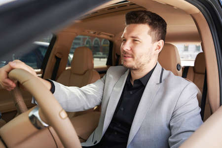 Businessman sitting in driver seat and driving car