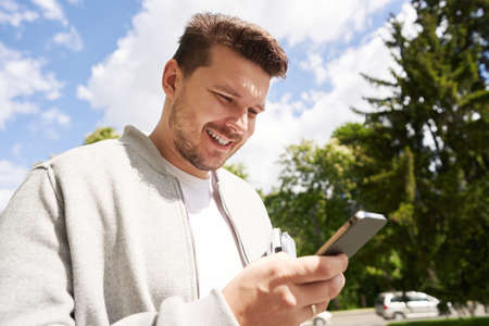 Happy man using modern smartphone on the street