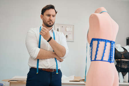 Male fashion designer making glamorous female dress in own atelierの写真素材
