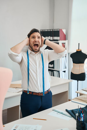 Couturier is screaming in a sewing workshop covering his ears