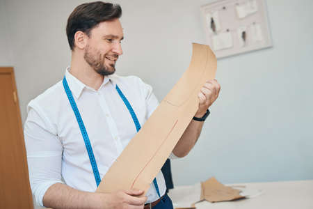 Man couturier examines a pattern in a sewing workshopの写真素材