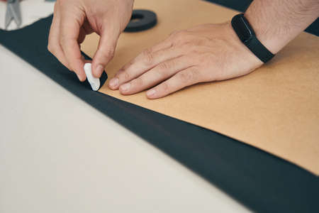 Designer is outlines the pattern on dark fabric by chalk