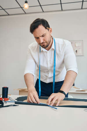 Couturier in sewing workshop measures borders of pattern on fabricの写真素材