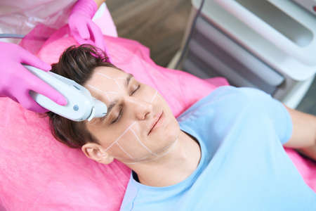 Man relaxing during smas lifting procedure in beauty clinic