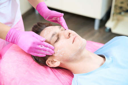 Young man during facial in cosmetologist office