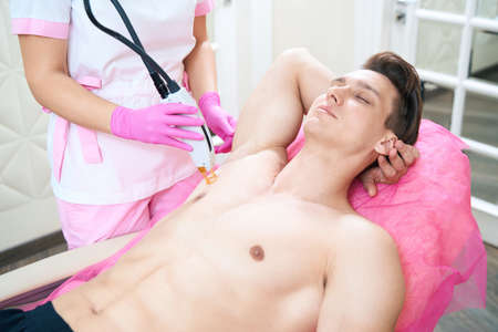 Man relaxing during laser epilation in beauty clinicの写真素材