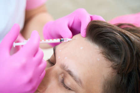 Beautician doing injections with antiage filler for manの写真素材