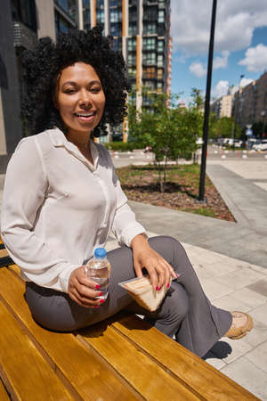 Multiracial female went out for lunch with a sandwich and water
