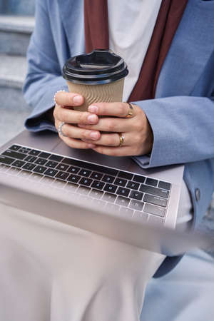 Woman holding coffee and laptop in her handsの写真素材