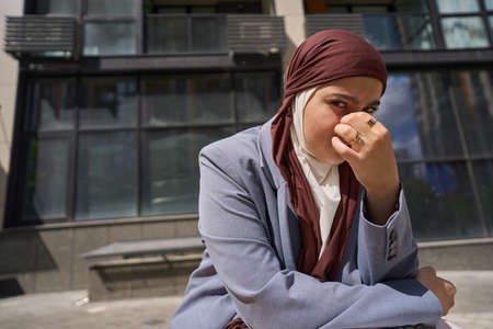 Arab woman feeling unwell and covering her nose with her hand