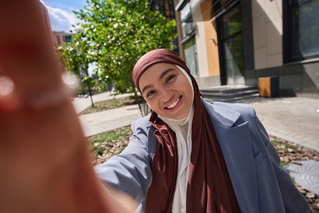 Arab woman in hijab taking a selfie on the phoneの写真素材