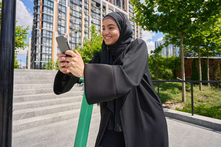 Young muslim woman with phone and scooterの写真素材