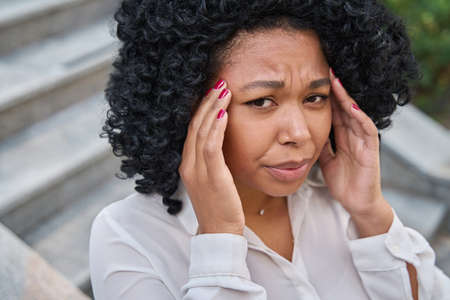 Woman clutches her temples and winces in pain