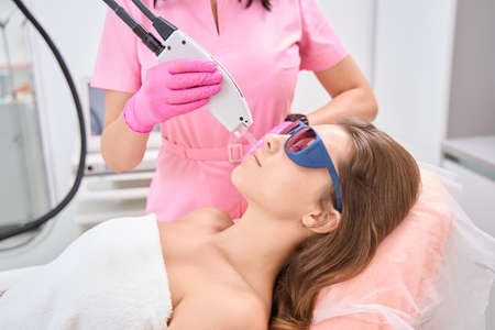 Lady lies with goggles on face during laser hair removalの写真素材