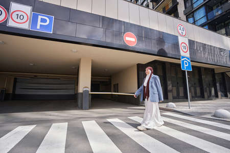 Arab woman crosses the road near the parking lot on a zebraの写真素材