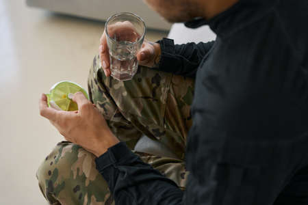 Military person opening pills container whileholding glass of waterの写真素材