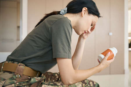 Woman has a headache, she is holding jar of pillsの写真素材