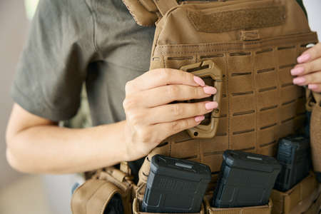 Woman soldier is wearing protective body armor and weapon set