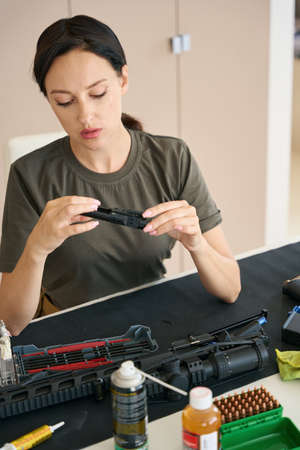 Woman examines a detail of a disassembled weaponの写真素材