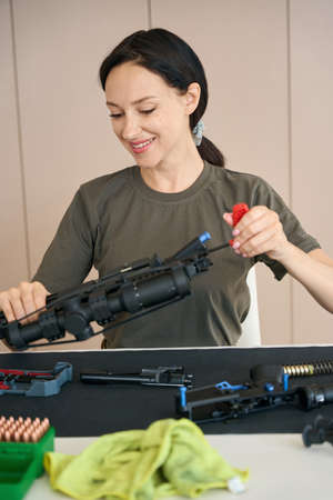 Woman cleaning machine gun with special tool