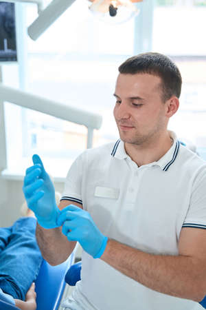 Experienced dentist protecting his hands before dental procedureの写真素材
