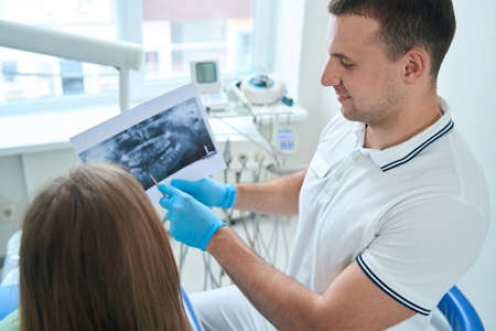 Male doctor showing panoramic radiograph to client during consultationの写真素材