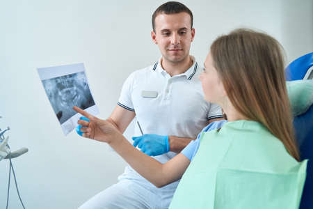 Young female patient discussing dental problems with doctor during consultationの写真素材