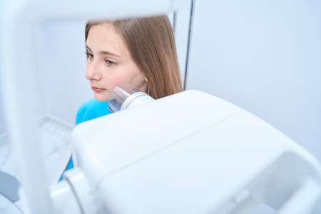 Tranquil teenage girl getting periapical x-ray in clinicの写真素材