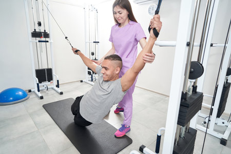 Smiling man doing physical therapy exercise with female instructor