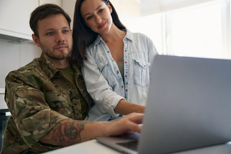 Cute couple in front of a laptop in bright roomの写真素材