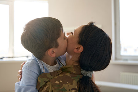 Boy hugs and kisses the mother of soldier on cheekの写真素材