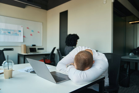 Tired man fell asleep at his desk in the officeの写真素材