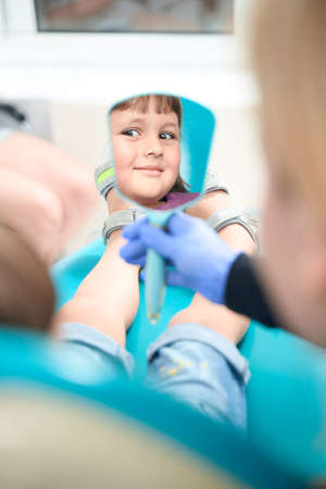 Pleased little girl seated in dental chairの写真素材