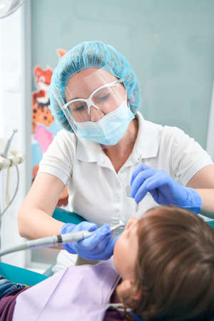 Pedodontist is performing dental procedure on little girlの写真素材