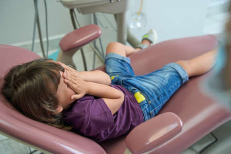 Frightened female child lying in dentist officeの写真素材
