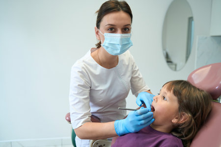 Pediatric dentist posing for camera during patient oral cavity examinationの写真素材