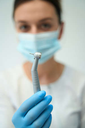 Female dentist showing medical equipment for caries treatment