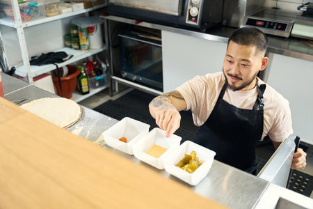 Handsome young chef preparing pizza toppings for cookingの写真素材