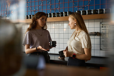 Two women drinking a drink in the kitchen while talking