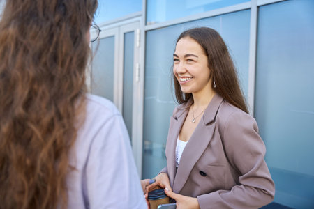 Young lady with long hair smiling in company of womanの写真素材