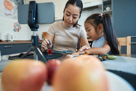 Woman blogger teaches her daughter how to do a manicureの写真素材