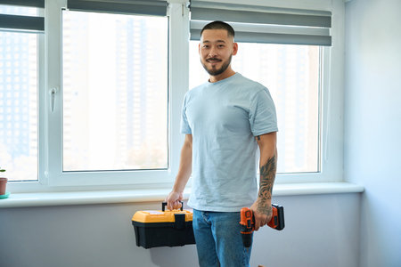 Asian man holding a toolbox and a screwdriver in his handsの写真素材