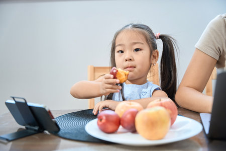 Asian girl sits in front phone and eats a peach