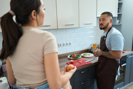 Asian couple cooking breakfast together in the kitchenの写真素材