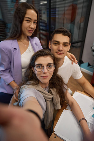 Three young employees take a cute selfie in the office
