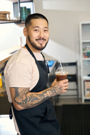 Good-looking guy working as barista and holding a drinkの写真素材
