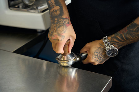 Skillful barista pressing fresh-grinded coffee grounds in holderの写真素材