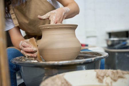 Woman potter forms earthenware on a potter wheelの写真素材